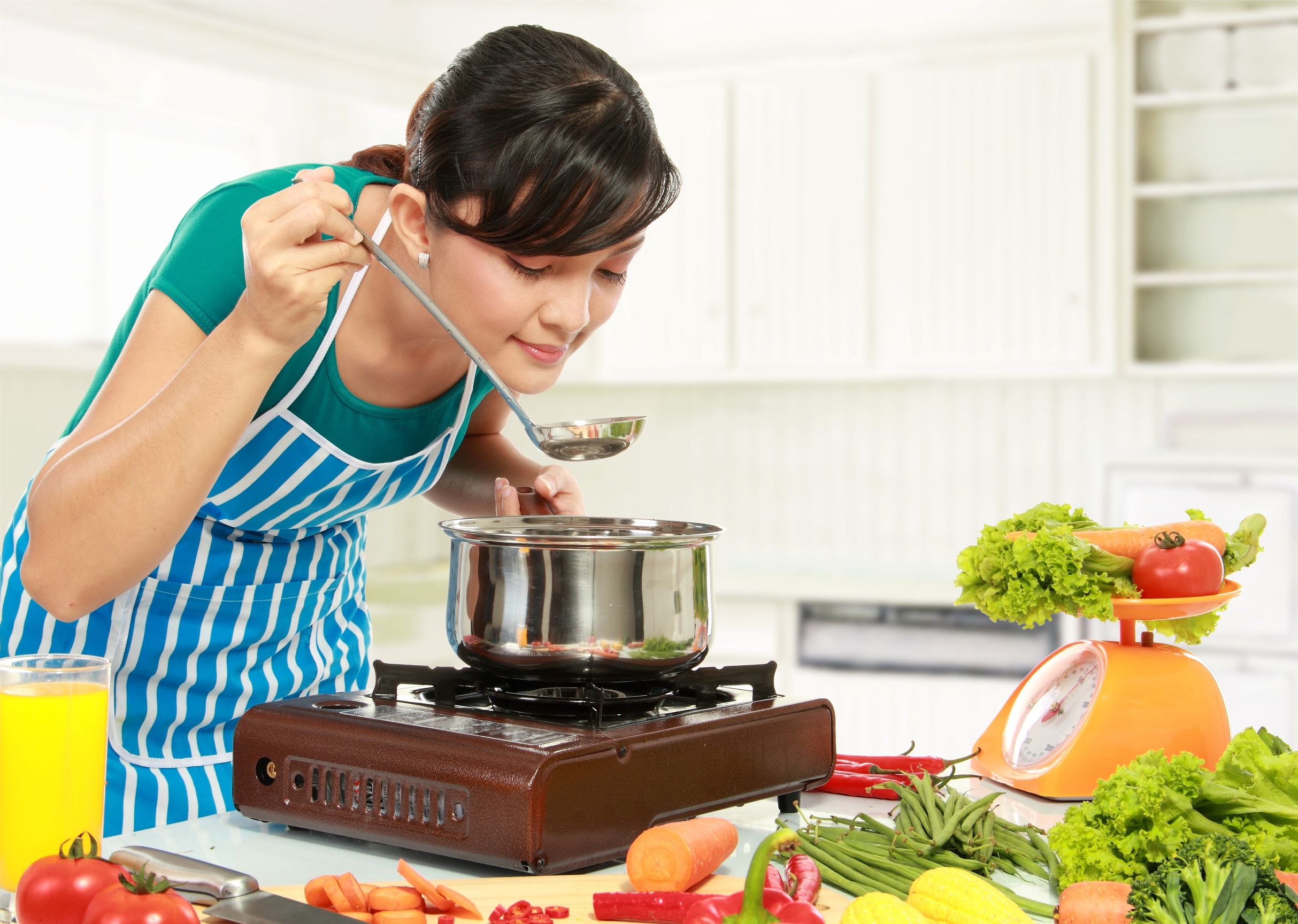 12371491 - young woman is tasting her cooking in the kitchen